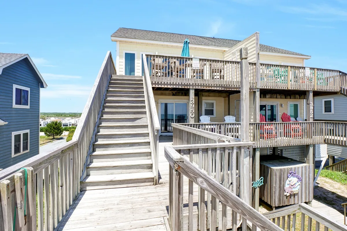 A welcoming upper deck features an array of colorful chairs and a dining table, ideal for outdoor meals and gatherings. The setting faces a beautiful sunset view, promising memorable evenings under open skies with loved ones.
